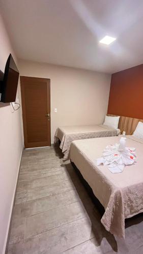 a hotel room with two beds and a door at Casarão Suítes Maragogi in Maragogi