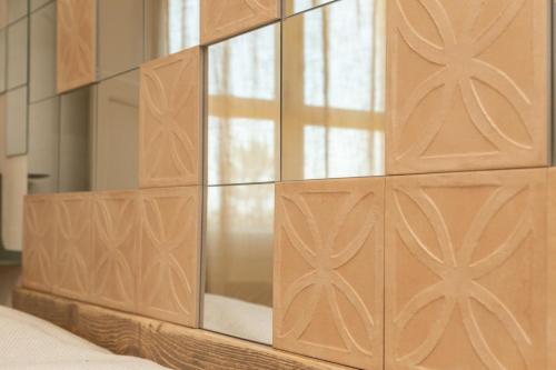 a wooden block wall with a mirror on top of a bed at Bixinau Camere Museo in Tortolì