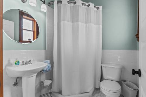 a bathroom with a white shower curtain and a sink at The Marquis Manor | JZ Vacation Rentals in Soulard