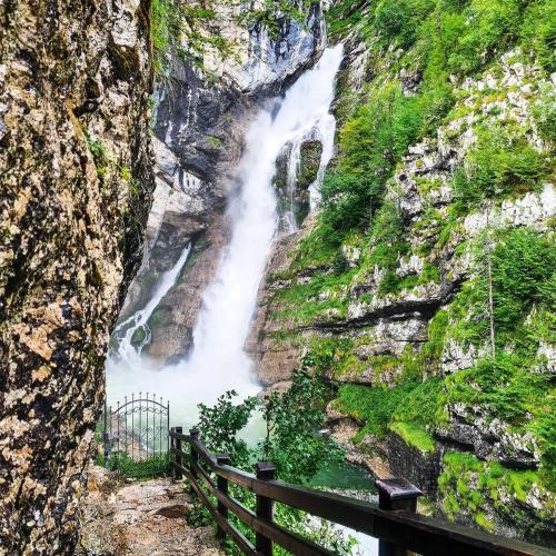 a waterfall on the side of a rocky mountain at Juliana Apartment Bohinj Lake in Bohinj