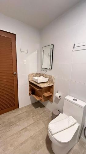 a bathroom with a white toilet and a sink at Casarão Suítes Maragogi in Maragogi