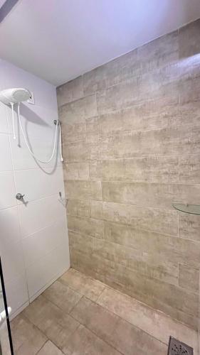 a bathroom with a shower and a stone wall at Casarão Suítes Maragogi in Maragogi