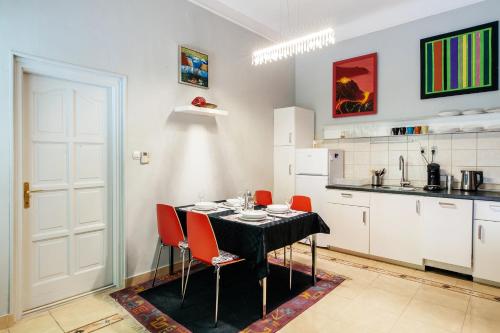 ブダペストにあるWind Queen Apartment with Air Conditionのキッチン(黒いテーブル、赤い椅子付)