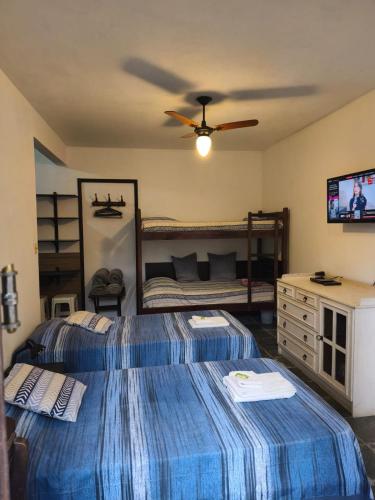 a bedroom with two beds and a television in it at Pousada Nascente do Pirahy in Piraí