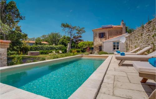 a swimming pool in front of a house with a stone wall at Pet Friendly Home In Osor in Osor