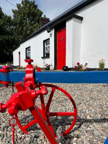 un vélo rouge posé sur des rochers devant une maison dans l'établissement Campbell's Cottage, à Blackwatertown