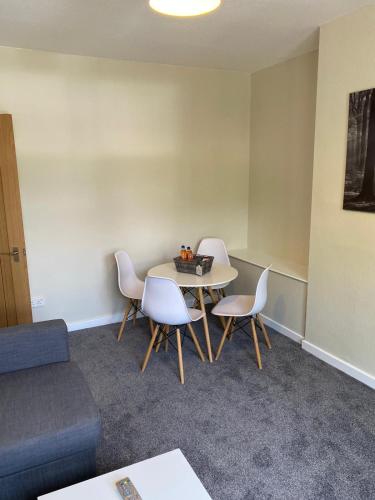 a room with a table and chairs and a couch at Glen Mhor - Beautiful two bedroom apartment Dunfermline in Townhill