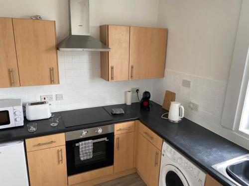 a kitchen with wooden cabinets and a dishwasher at Glen Mhor - Beautiful two bedroom apartment Dunfermline in Townhill