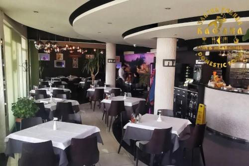 a restaurant with white tables and chairs and a bar at Kafana Zlatna Ribica in Golubac