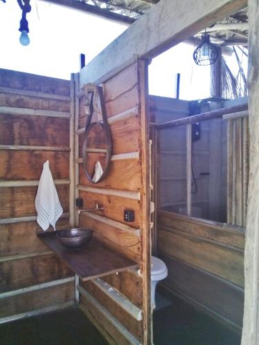 a bathroom with a wooden wall with a sink and a bowl at Odara Glamping-Jalapão in Mateiros