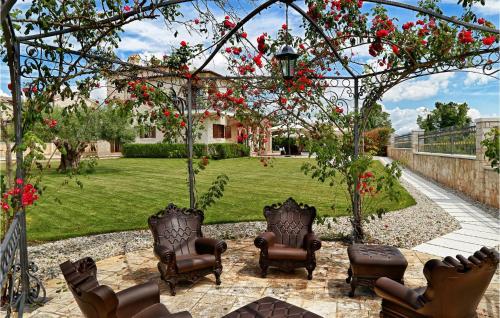 a garden with chairs and a pergola with red flowers at Villa Carolus Barat in Barat