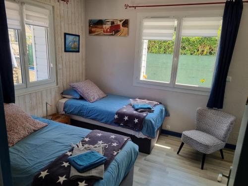 Cette chambre comprend deux lits, une chaise et deux fenêtres. dans l'établissement L'écume de mer, véritable maison de vacances à 500 m des plages, à Saint-Malo