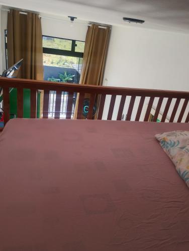 a bed with a red bedspread and a window at Pousada Mar e Chaves in Penha