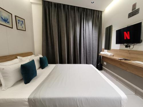a bedroom with a large white bed with a television at KANT by GoHotels - Near Shree Dwarkadhish Temple in Dwarka