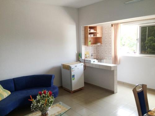 a living room with a blue couch and a kitchen at Appartements Lome Marie Antoinette in Atigan