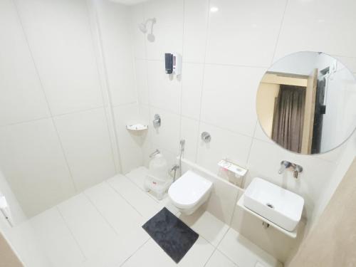 a white bathroom with a toilet and a mirror at KANT by GoHotels - Near Shree Dwarkadhish Temple in Dwarka