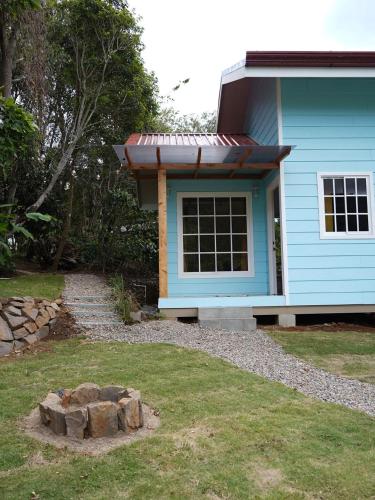 a blue house with a pile of logs in front of it at Tiny House at Finca Haug in San Pablo