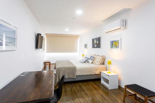 a bedroom with a bed and a wooden table at Cobertura com linda vista da praia do Pêpe in Búzios
