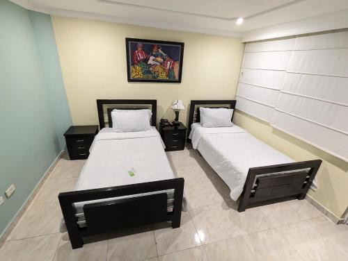a bedroom with two beds and a painting on the wall at Hotel Sweet Home in Bogotá