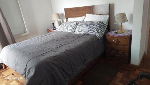 Un dormitorio con una cama y una mesita de noche con una lámpara. en Stay Green Charm, en Cochabamba