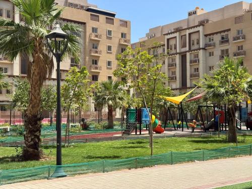 a playground in a park with palm trees and buildings at Mabaat-Superior 2BR- Sama Jeddah 609 in Jeddah