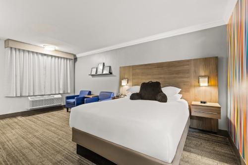 a hotel room with a large bed and blue chairs at Signature Temecula in Temecula