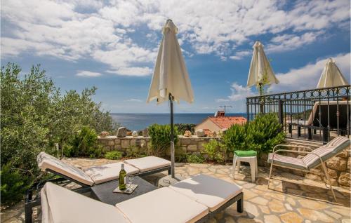un patio avec deux parasols et l'océan dans l'établissement Beach Front Home In Miholascica With Private Swimming Pool, Can Be Inside Or Outside, à Miholašćica