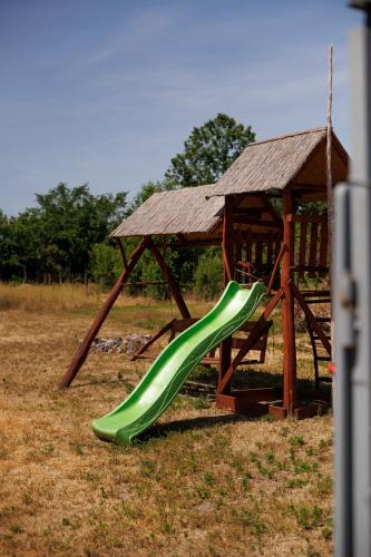 a green slide in a playground with a gazebo at Forrás Vendégház in Mórahalom