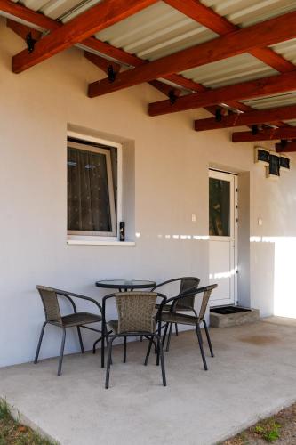 a patio with chairs and a table and a window at Forrás Vendégház in Mórahalom