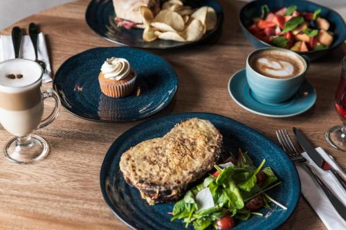 a wooden table with plates of food and cups of coffee at Hotel Poblado Plaza in Medellín