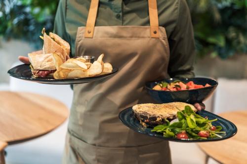 a person is holding two plates of food at Hotel Poblado Plaza in Medellín