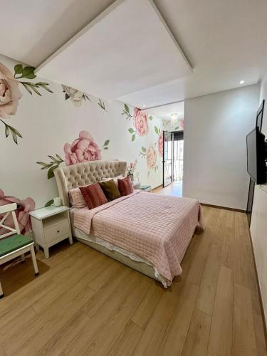 a bedroom with a bed with flowers on the wall at Appartement à louer in Nouaceur