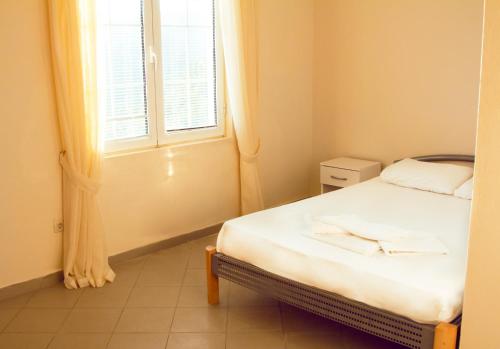 a small bedroom with a bed and a window at Vila Kraljica Snežna in Sutomore