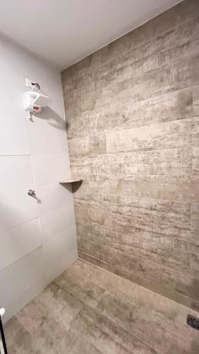a bathroom with a shower with a stone wall at Casarão Suítes Maragogi in Maragogi