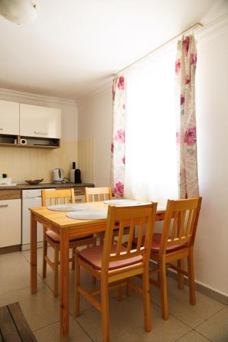 a kitchen with a wooden dining table and chairs at Forrás Vendégház in Mórahalom