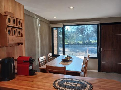 a dining room with a table and a large window at Cabañas Indómita in El Bolsón