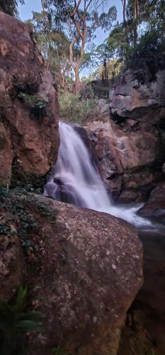 a waterfall in the middle of a river with rocks at Green Flowers Farm in Córrego do Bom Jesus