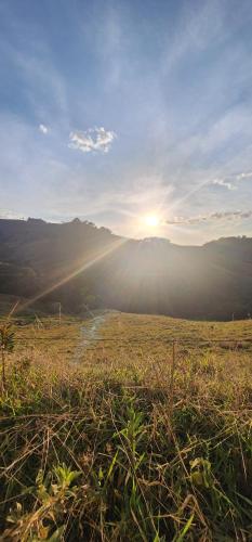 a field with the sun shining on the horizon at Green Flowers Farm in Córrego do Bom Jesus