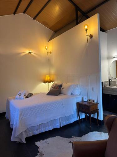 a bedroom with a white bed and a table at Green Flowers Farm in Córrego do Bom Jesus