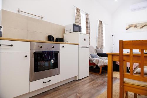 a kitchen with white appliances and a dining room at Forrás Vendégház in Mórahalom