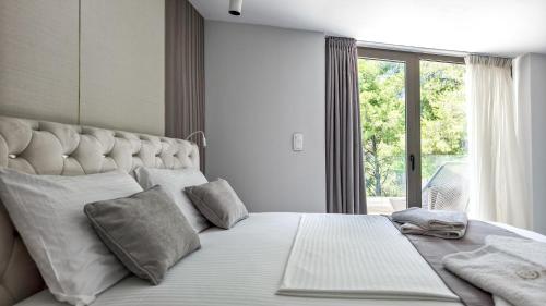 a bedroom with a large white bed with a window at Alessandra Luxury Villas with Private Pools and Jacuzzi in Kriopigi