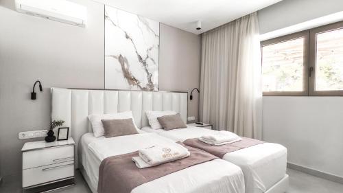 a bedroom with two beds and a window at Alessandra Luxury Villas with Private Pools and Jacuzzi in Kriopigi