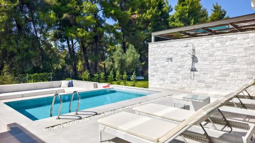 a swimming pool with two chairs and a table and a pool at Alessandra Luxury Villas with Private Pools and Jacuzzi in Kriopigi