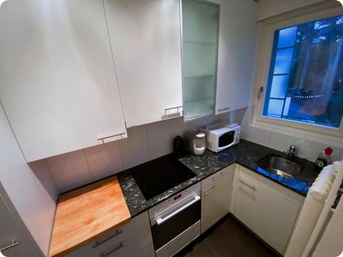a small kitchen with white cabinets and a sink at HSH Monbijou - Serviced Junior Suite with balcony Bern City in Bern