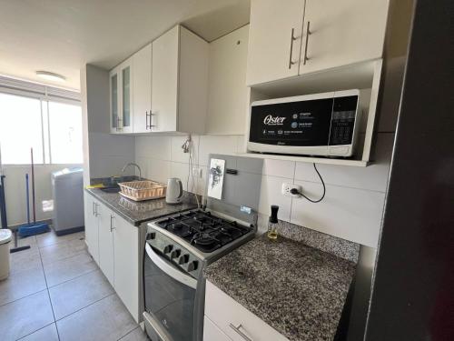 a kitchen with a stove and a microwave at Hermoso departamento totalmente amoblado - Lte San Miguel in Lima