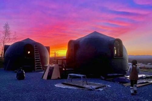 a child standing in front of two dome shaped buildings at EcoDomes con vistas a Denali Talkeetna, Alaska, Estados Unidos in Talkeetna