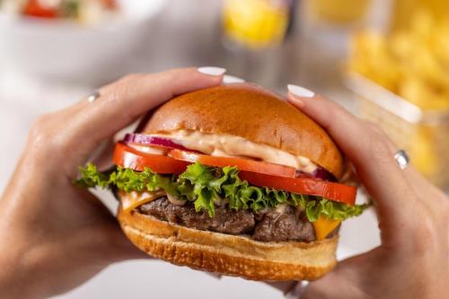 a person holding a hamburger in their hands at Moon Palace The Grand Cancun All Inclusive in Cancún