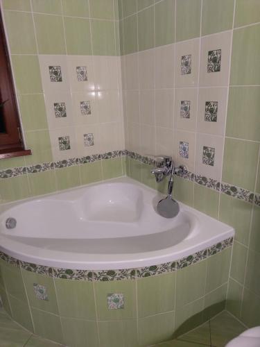 a bath tub in a green tiled bathroom at Villa Flower Deluxe II in Dunajská Streda