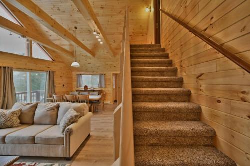 a staircase in a wooden house with a couch at NEW ! Lake front Lookout Log Cabin! Private Lake ! in Leonardsville