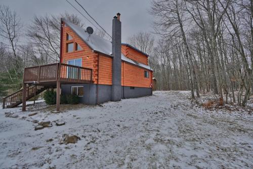 a wooden house with a deck in the snow at NEW ! Lake front Lookout Log Cabin! Private Lake ! in Leonardsville